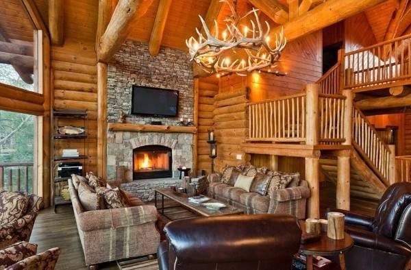 Интерьер зала с камином в частном доме из бруса